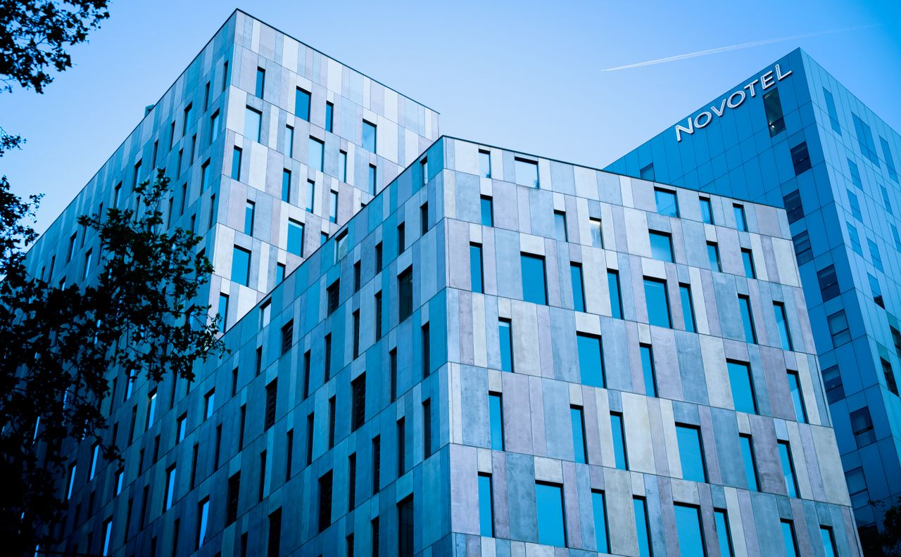 Home Blue-toned modern architecture of Novotel in Barcelona under a clear sky.